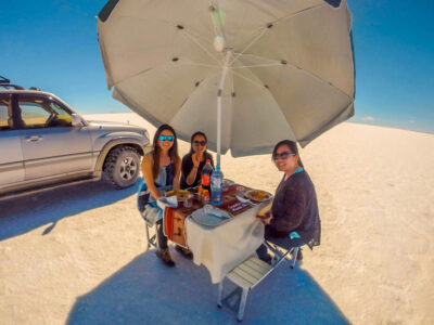 Small group of tourists enjoying a picnic lunch during a Salar de Uyuni Travel experience in Bolivia